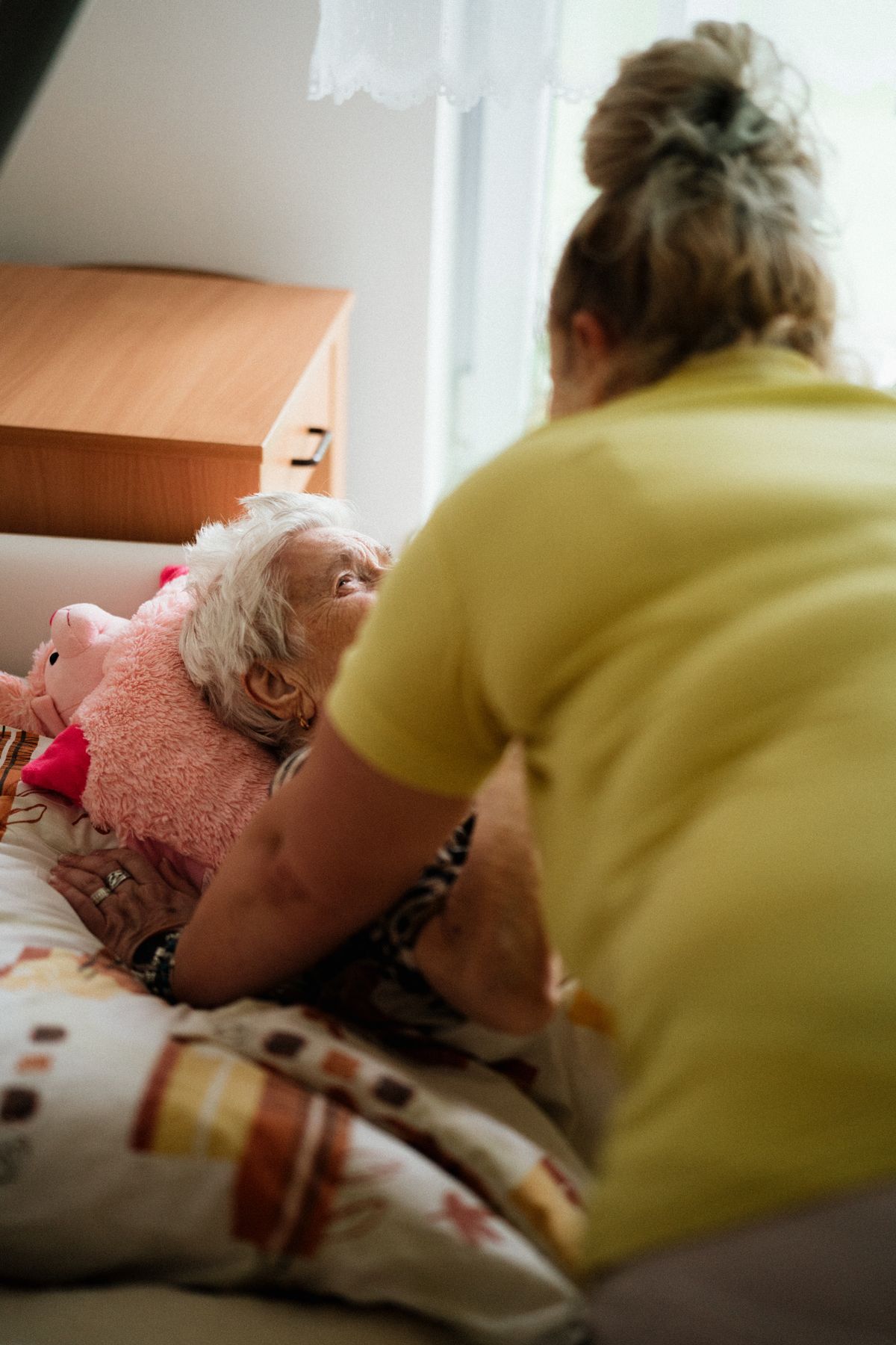 A nurse assists an elderly woman in a comfortable care setting.