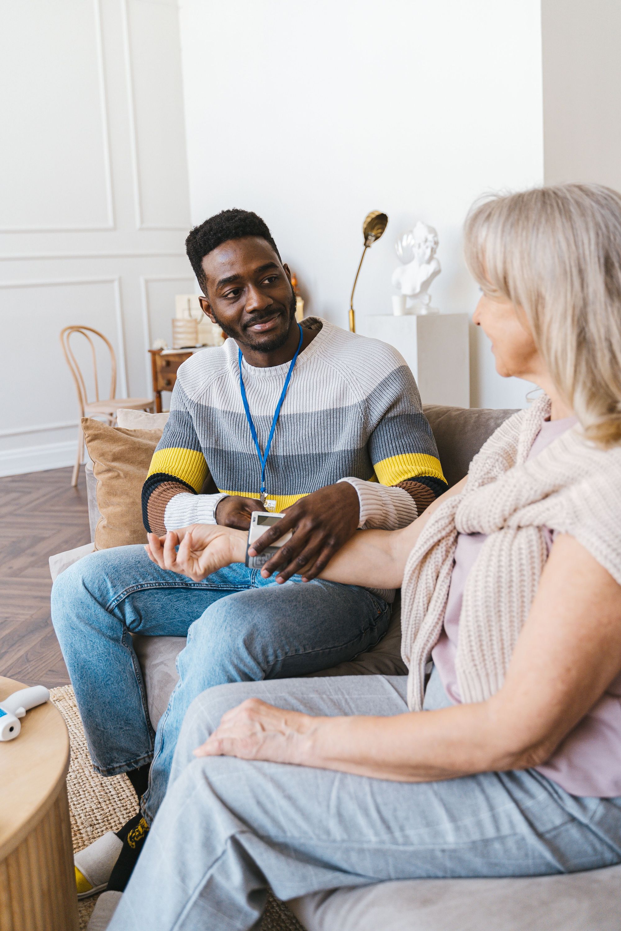 A home health aide checking a client's blood pressure in her living room.